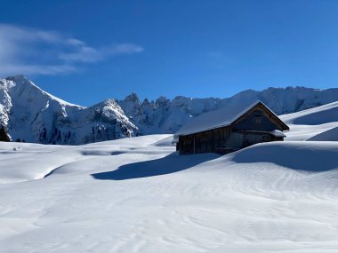 İsviçre dağ kulübeleri kışlık giysiler içinde ve Alpstein dağ sırasının yamaçlarında taze bir kar örtüsüyle Schwaegalp, İsviçre (Schweiz)