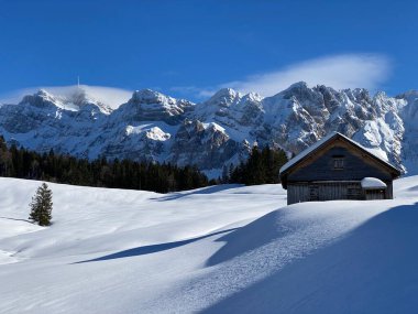 İsviçre dağ kulübeleri kışlık giysiler içinde ve Alpstein dağ sırasının yamaçlarında taze bir kar örtüsüyle Schwaegalp, İsviçre (Schweiz)