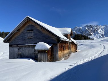 İsviçre dağ kulübeleri kışlık giysiler içinde ve Alpstein dağ sırasının yamaçlarında taze bir kar örtüsüyle Schwaegalp, İsviçre (Schweiz)
