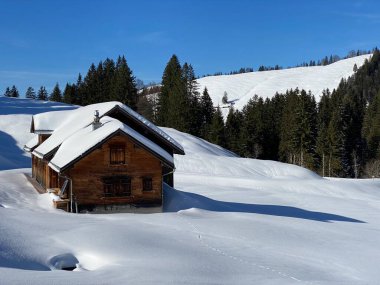 İsviçre dağ kulübeleri kışlık giysiler içinde ve Alpstein dağ sırasının yamaçlarında taze bir kar örtüsüyle Schwaegalp, İsviçre (Schweiz)