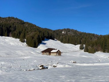 İsviçre dağ kulübeleri kışlık giysiler içinde ve Alpstein dağ sırasının yamaçlarında taze bir kar örtüsüyle Schwaegalp, İsviçre (Schweiz)