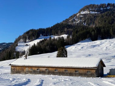 İsviçre dağ kulübeleri kışlık giysiler içinde ve Alpstein dağ sırasının yamaçlarında taze bir kar örtüsüyle Schwaegalp, İsviçre (Schweiz)
