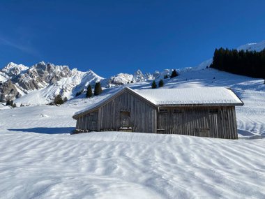 İsviçre dağ kulübeleri kışlık giysiler içinde ve Alpstein dağ sırasının yamaçlarında taze bir kar örtüsüyle Schwaegalp, İsviçre (Schweiz)