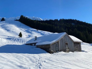 İsviçre dağ kulübeleri kışlık giysiler içinde ve Alpstein dağ sırasının yamaçlarında taze bir kar örtüsüyle Schwaegalp, İsviçre (Schweiz)