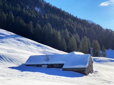 İsviçre dağ kulübeleri kışlık giysiler içinde ve Alpstein dağ sırasının yamaçlarında taze bir kar örtüsüyle Schwaegalp, İsviçre (Schweiz)