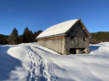 İsviçre dağ kulübeleri kışlık giysiler içinde ve Alpstein dağ sırasının yamaçlarında taze bir kar örtüsüyle Schwaegalp, İsviçre (Schweiz)