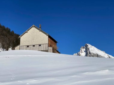 İsviçre çayırlarındaki yerli dağ kulübeleri ve ahşap ahırlar taze beyaz kar örtüsüyle kaplıdır, Alt St. Johann - Obertoggenburg, İsviçre (Schweiz)