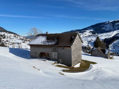 İsviçre çayırlarındaki yerli dağ kulübeleri ve ahşap ahırlar taze beyaz kar örtüsüyle kaplıdır, Alt St. Johann - Obertoggenburg, İsviçre (Schweiz)
