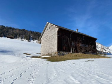 İsviçre çayırlarındaki yerli dağ kulübeleri ve ahşap ahırlar taze beyaz kar örtüsüyle kaplıdır, Alt St. Johann - Obertoggenburg, İsviçre (Schweiz)