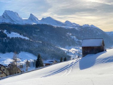 İsviçre çayırlarındaki yerli dağ kulübeleri ve ahşap ahırlar taze beyaz kar örtüsüyle kaplıdır, Alt St. Johann - Obertoggenburg, İsviçre (Schweiz)