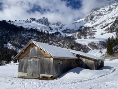 Yerli alp kulübeleri ve İsviçre çayırlarındaki ahşap ahırlar taze beyaz kar örtüsüyle kaplıdır, Unterwasser - Obertoggenburg, İsviçre (Schweiz)