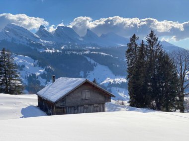 Yerli alp kulübeleri ve İsviçre çayırlarındaki ahşap ahırlar taze beyaz kar örtüsüyle kaplıdır, Unterwasser - Obertoggenburg, İsviçre (Schweiz)