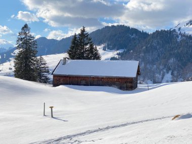 Yerli alp kulübeleri ve İsviçre çayırlarındaki ahşap ahırlar taze beyaz kar örtüsüyle kaplıdır, Unterwasser - Obertoggenburg, İsviçre (Schweiz)