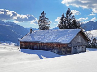 Yerli alp kulübeleri ve İsviçre çayırlarındaki ahşap ahırlar taze beyaz kar örtüsüyle kaplıdır, Unterwasser - Obertoggenburg, İsviçre (Schweiz)
