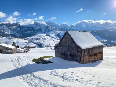 Yerli alp kulübeleri ve İsviçre çayırlarındaki ahşap ahırlar taze beyaz kar örtüsüyle kaplıdır, Unterwasser - Obertoggenburg, İsviçre (Schweiz)