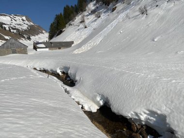 Glarus Alpleri dağ kütlesi İsviçre / Schweiz 'deki Kloentalersee Gölü (Kloentalersee veya Klontaler Gölü) üzerinde toplanan Sulzbach deresi boyunca eriyen karla ilkbahar atmosferi