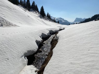Glarus Alpleri dağ kütlesi İsviçre / Schweiz 'deki Kloentalersee Gölü (Kloentalersee veya Klontaler Gölü) üzerinde toplanan Sulzbach deresi boyunca eriyen karla ilkbahar atmosferi
