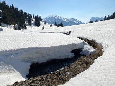 Glarus Alpleri dağ kütlesi İsviçre / Schweiz 'deki Kloentalersee Gölü (Kloentalersee veya Klontaler Gölü) üzerinde toplanan Sulzbach deresi boyunca eriyen karla ilkbahar atmosferi