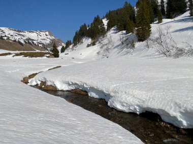 Glarus Alpleri dağ kütlesi İsviçre / Schweiz 'deki Kloentalersee Gölü (Kloentalersee veya Klontaler Gölü) üzerinde toplanan Sulzbach deresi boyunca eriyen karla ilkbahar atmosferi