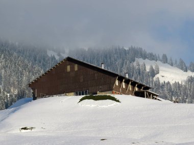 İsviçre çayırlarındaki yerli dağ kulübeleri ve ahşap ahırlar taze beyaz kar örtüsüyle kaplıdır, Nesslau - Obertoggenburg, İsviçre (Schweiz)
