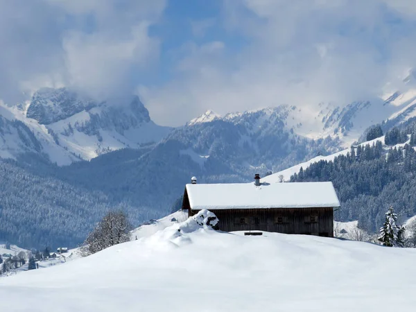 スイスの牧草地に新鮮な白い雪に覆われた先住民の高山の小屋と木製の牛の厩舎 Nesslau Obertoggenburg スイス スイス — ストック写真