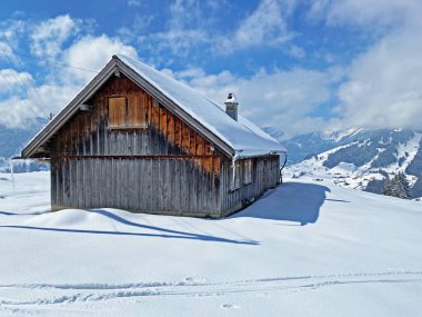 İsviçre çayırlarındaki yerli dağ kulübeleri ve ahşap ahırlar taze beyaz kar örtüsüyle kaplıdır, Nesslau - Obertoggenburg, İsviçre (Schweiz)