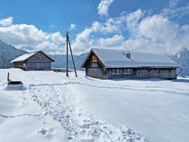 İsviçre çayırlarındaki yerli dağ kulübeleri ve ahşap ahırlar taze beyaz kar örtüsüyle kaplıdır, Nesslau - Obertoggenburg, İsviçre (Schweiz)