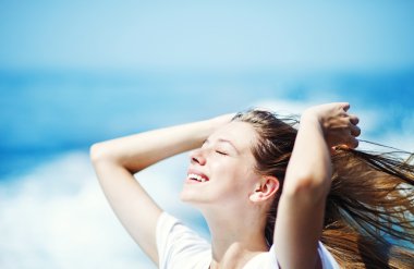 Young beautiful woman with streaming hair in front of the ocean clipart