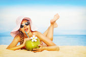 junge Frau im rosa Badeanzug mit Kokoscocktail am Strand, bali
