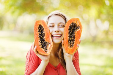 papaya ile gülümseyen genç bir kadın