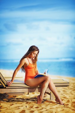 genç güzel kadın kumsalda okuma