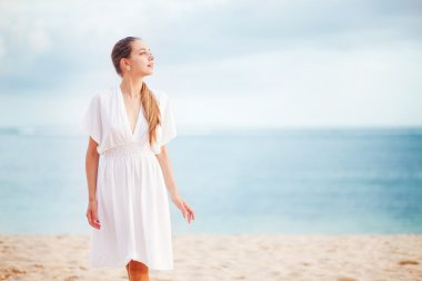 okyanus kıyısında beyaz elbiseli genç kadın
