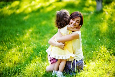 güzel genç anne ve kızı yeşil çimenlerin üzerinde eğleniyor