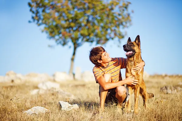 Pojke med en hund i ett fält — Stockfoto