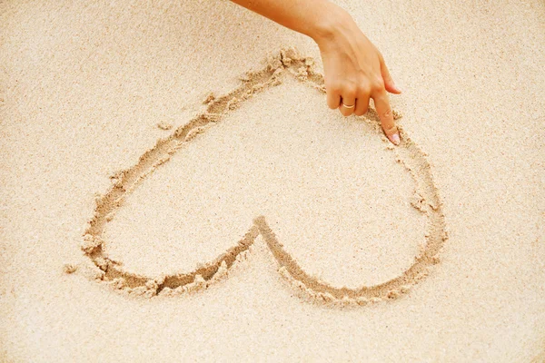 Mulher na praia fazendo coração na areia — Fotografia de Stock