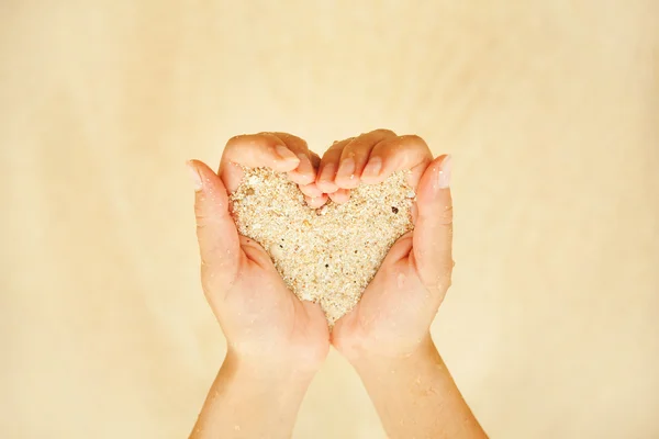 Sand in hands in heart shape — Stock Photo, Image