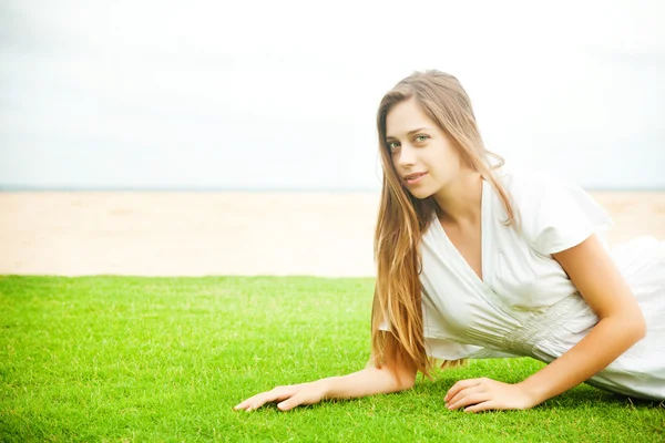 Jonge mooie vrouw op het groene gras — Stockfoto
