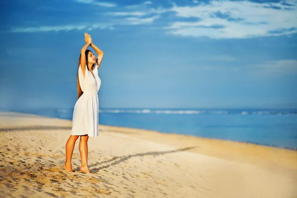 Jonge vrouw aan de oever van de Oceaan in witte jurk — Stockfoto