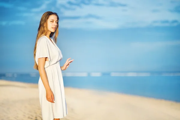 Jonge vrouw aan de oever van de Oceaan in witte jurk — Stockfoto