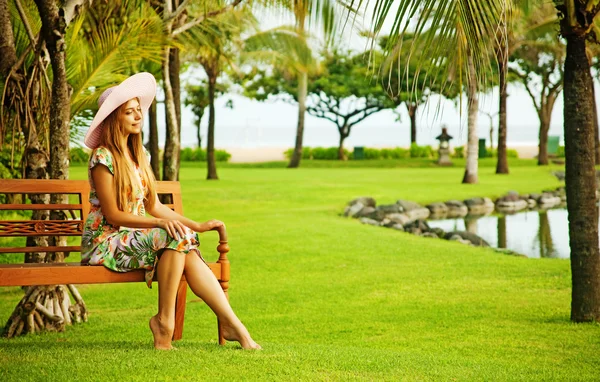 Young woman sitting on the bench in park — Stock Photo, Image