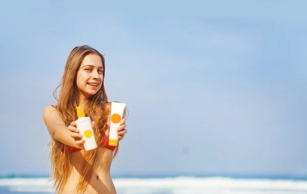 Portret van vrouw nemen huidverzorging met zonnebrand lotion op strand — Stockfoto