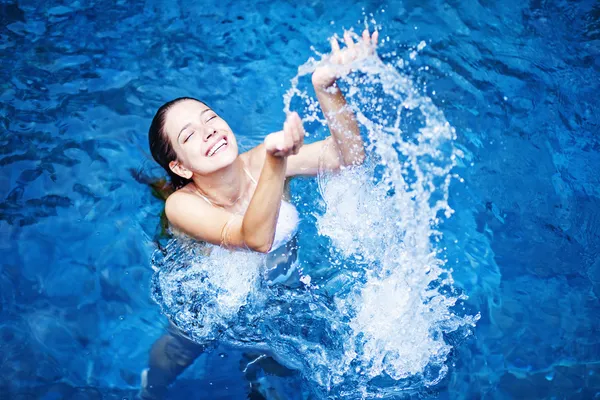 Unga vackra kvinnan stänkande vatten i poolen — Stockfoto