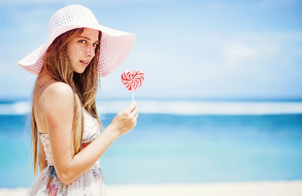 Valentine's day: Young caucasian woman holding lollipop-heart on the beach — Stock Photo, Image