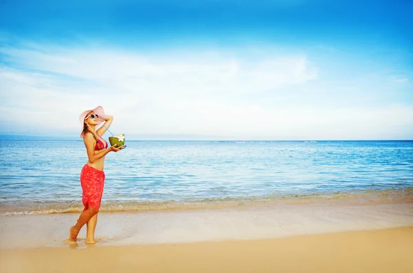 Młoda kobieta w różowy strój kąpielowy z kokos koktajl na plaży, bali — Zdjęcie stockowe