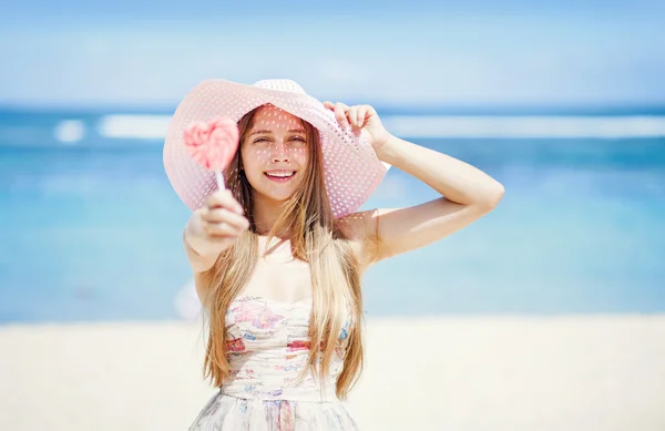 San Valentino: Giovane donna caucasica con in mano un lecca-lecca-cuore sulla spiaggia — Foto Stock