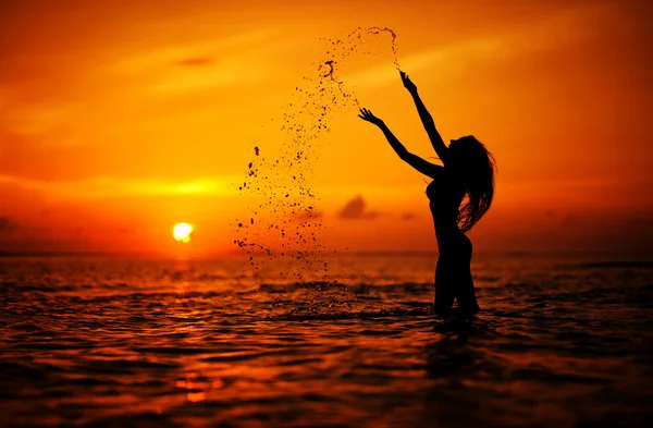Long hair woman silhouette in the sea splashing water — Stock Photo, Image