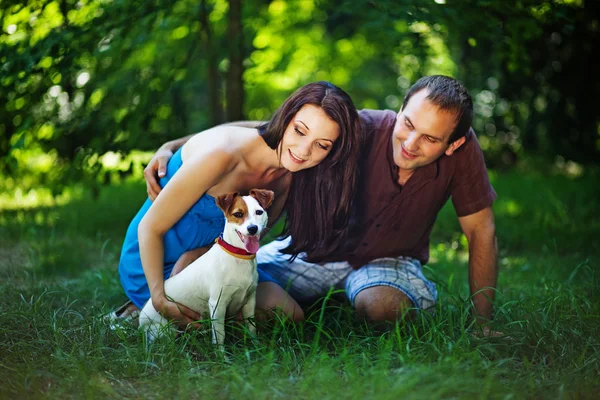 Jovem casal com cão em piquenique no parque — Fotografia de Stock