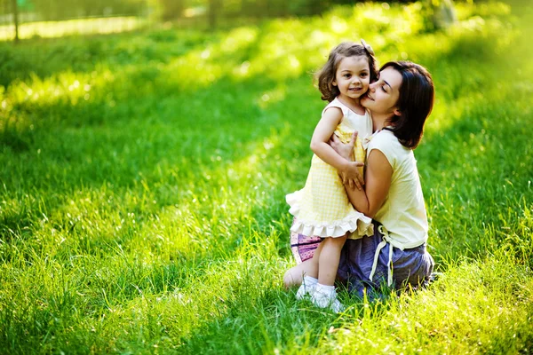 Mooie jonge moeder en haar dochter plezier op het groene gras — Stockfoto