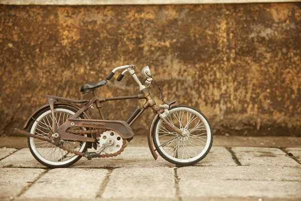 An old, rusty white bicycle leaning against a grungy wall in bali — Stock Photo, Image