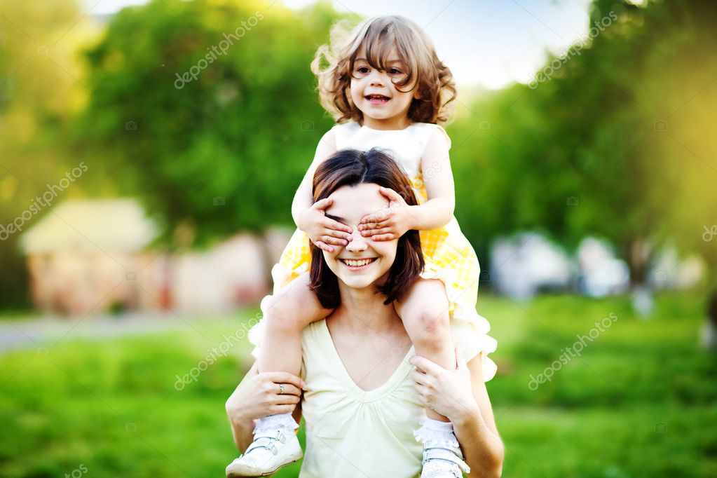 beautiful little and happy daughter with her hands on eyes of her mother.